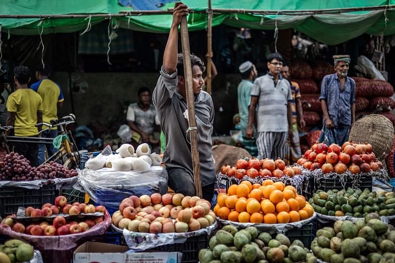 A vendor waits for customers at his fruits stall at a wholesale market in Dhaka on 14 August 2024, days after a student-led uprising that ended the 15-year rule of Sheikh Hasina